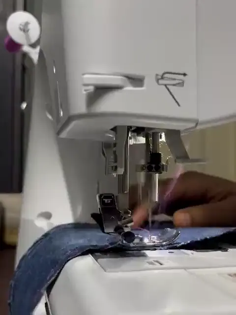 Una máquina de coser trabajando sobre una tela de mezclilla